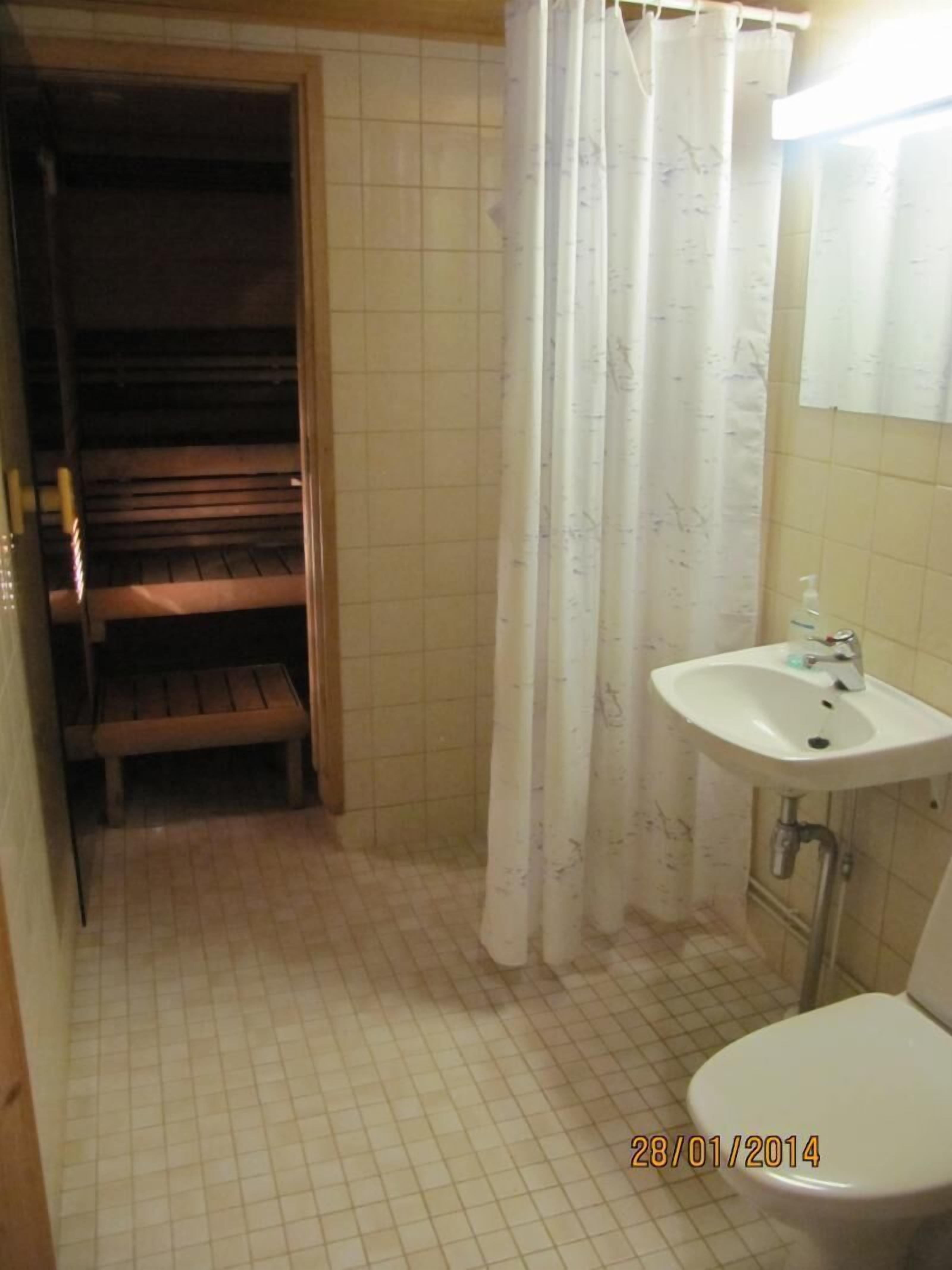 A small bathroom with a toilet, sink, and wooden bench.