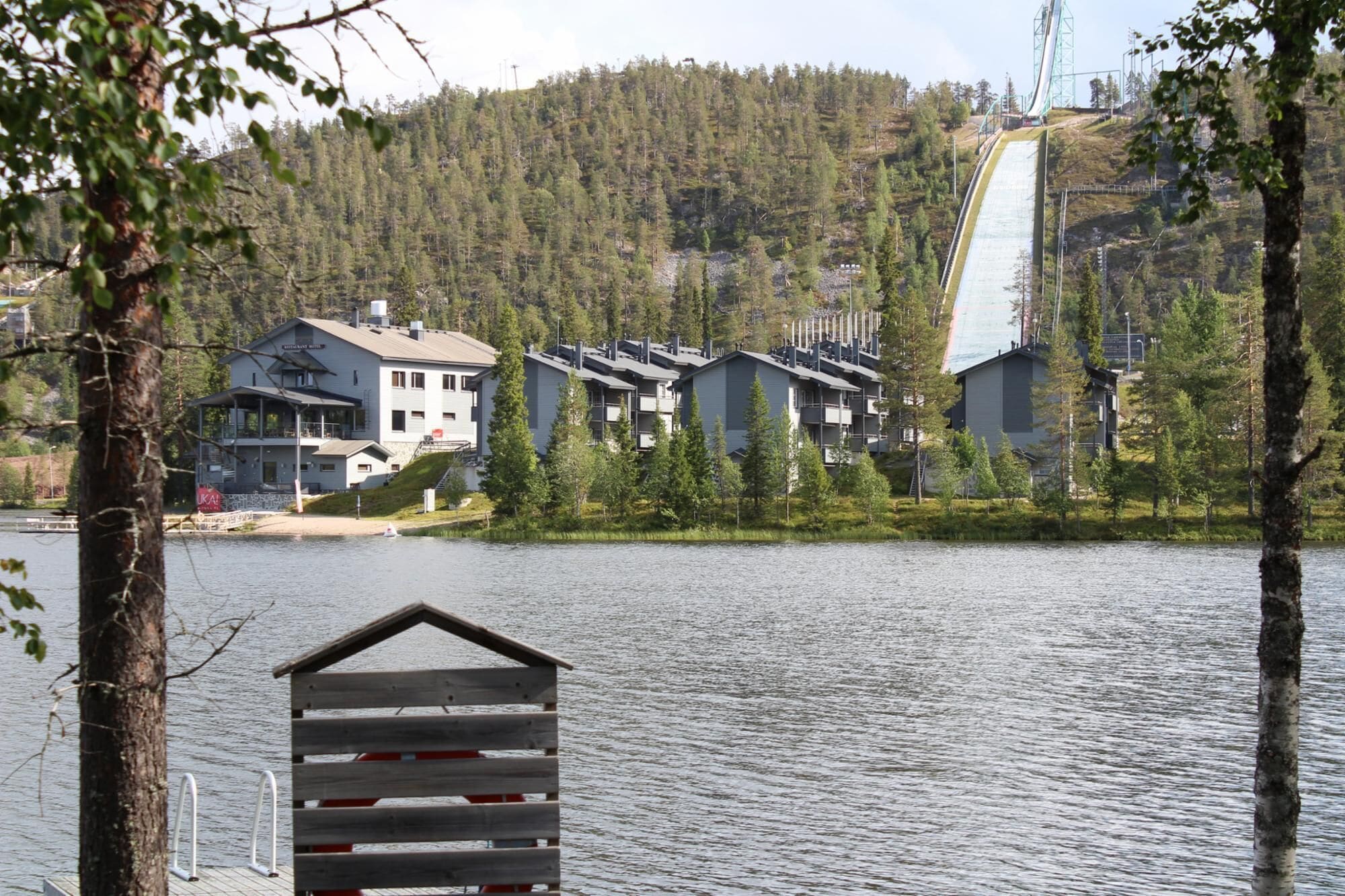 Una propiedad frente al lago con edificios modernos, un muelle y una ladera boscosa.