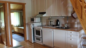 Una cocina compacta equipada con microondas, estufa, refrigerador y lavamanos.