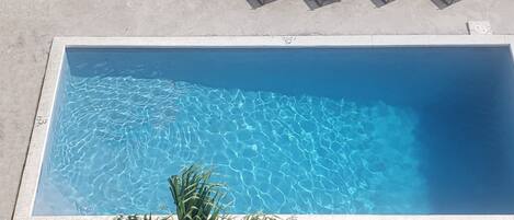 Una piscina rectangular con agua cristalina y un borde de hormigón.