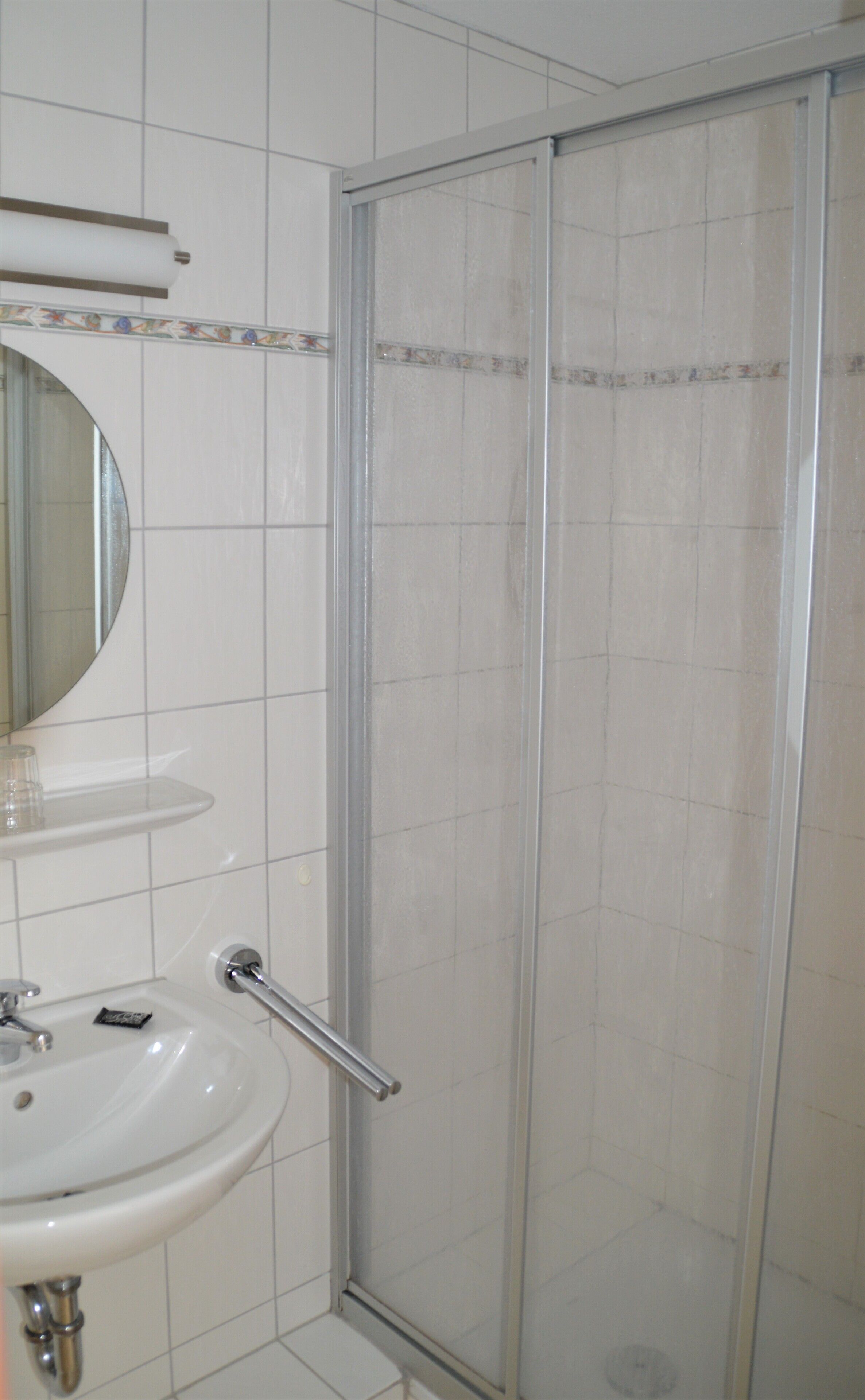 A bathroom with a white sink, a mirror, and a glass shower enclosure.