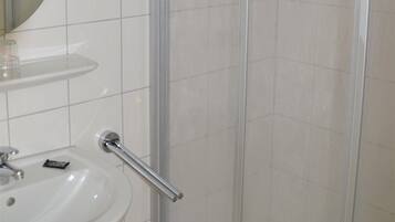 A bathroom with a white sink, a mirror, and a glass shower enclosure.