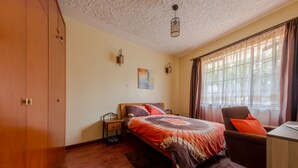 Une chambre à coucher avec un lit, un bureau, une chaise, une armoire et un tableau accroché au mur.