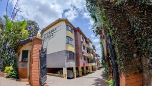 Un hôtel à plusieurs étages, doté d’une façade en briques et d’une entrée fermée par un portail.
