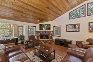 A spacious living room with a fireplace, leather sofas, and a pool table.