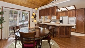 A spacious kitchen with wooden cabinets, a central island, and a dining area with a round table and chairs.