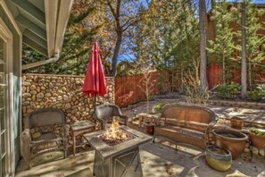 An outdoor patio area with stone walls, wicker furniture, and a fire pit.