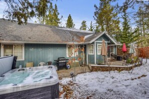 A house with a hot tub, a barbecue grill, and a covered patio area.