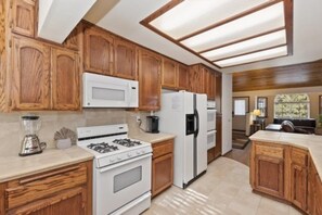 Una cocina con armarios de madera, una estufa blanca, un refrigerador y un microondas.