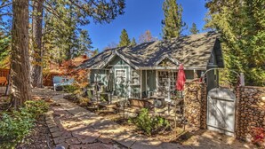 A house with a stone wall, a covered porch, and a patio area with outdoor furniture.