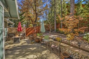 Un patio al aire libre con paredes de piedra, un hogar para fuego y mobiliario exterior.