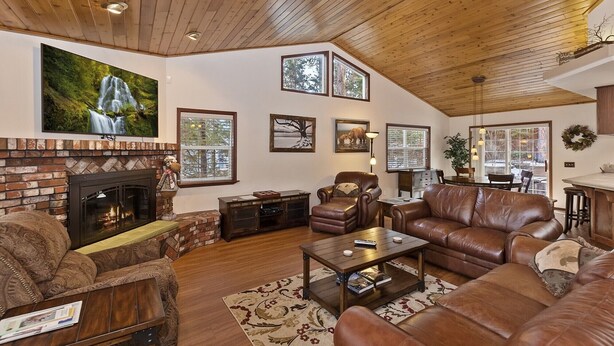 A spacious living room with a fireplace, leather sofas, a coffee table, and artwork on the walls.