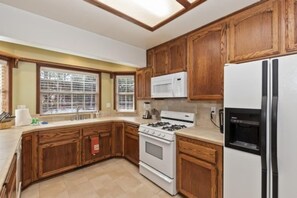 Una cocina con armarios de madera, estufa blanca, microondas y refrigerador.