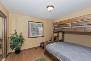 Habitación con literas, una ventana, una planta en maceta y una lámpara en el techo.