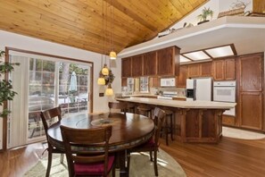 Una cocina amplia con armarios de madera, una isla central y un comedor con una mesa redonda y sillas.