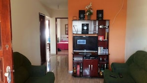 A living room with a TV, entertainment unit, and two green sofas. - Casa de Praia Cordeirinho (Marica)