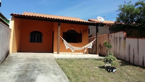 A house with a tiled roof, a satellite dish, a hammock, and a small tree in the yard. - Casa de Praia Cordeirinho (Marica)