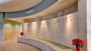 Et receptionsområde med en buet marmorvæg og et skilt, der viser "MAJESTIC BEACH TOWERS".