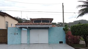 Un edificio residencial con techo de tejas, pared exterior azul y entrada con portón.
