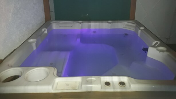 Un jacuzzi con luz morada, un panel de control y un desagüe.