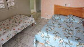 Un dormitorio con dos camas, una con colcha de motivos florales y la otra con diseño de pájaros.