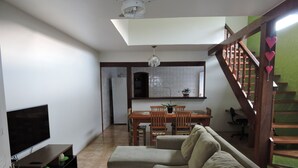 Una sala de estar con sofá, televisor y una escalera.
