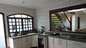 Una cocina con gabinetes blancos, una estufa, un fregadero y un ventanal con vistas al exterior.