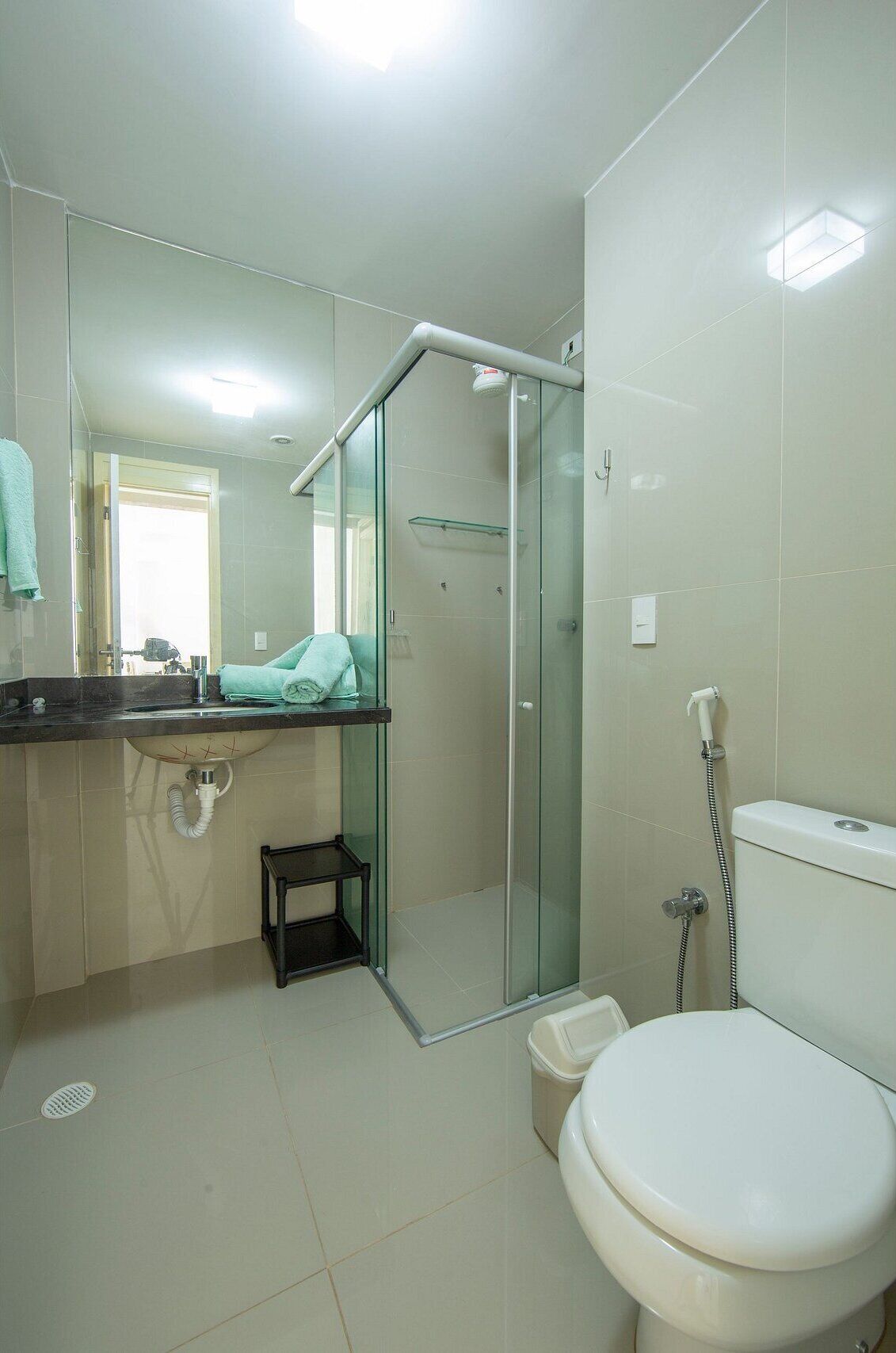 Une salle de bain moderne avec une douche à parois de verre, des toilettes et un lavabo avec un miroir au-dessus.