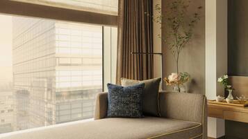 Un salón moderno con un sofá, un florero con flores y vistas a un edificio a través de grandes ventanales.