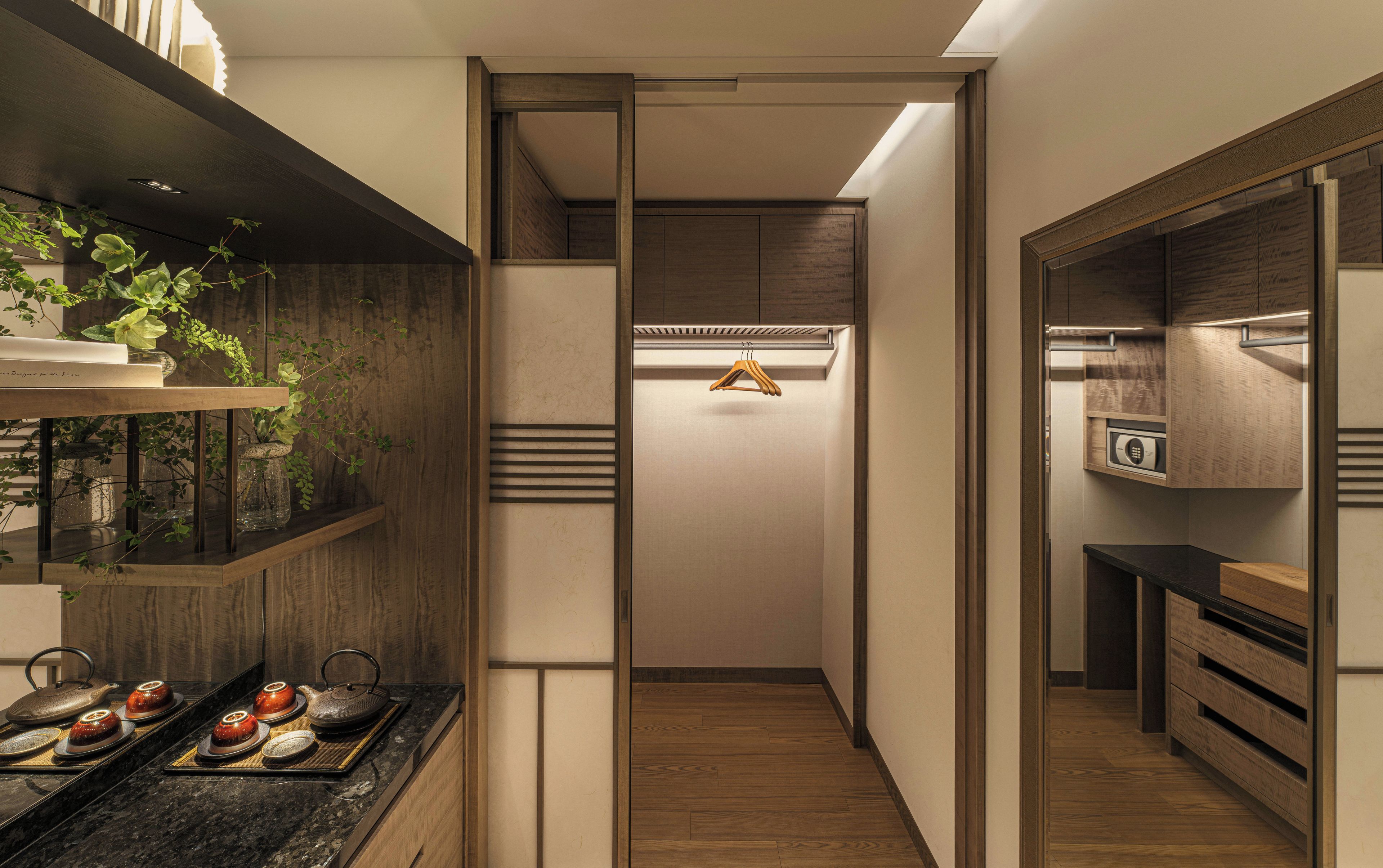 A modern kitchen with wooden cabinets, a countertop with tea sets, and a hanging clothes rack.