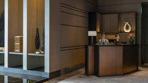 A modern reception desk with a concierge area, wooden paneling, and a decorative vase with flowers.