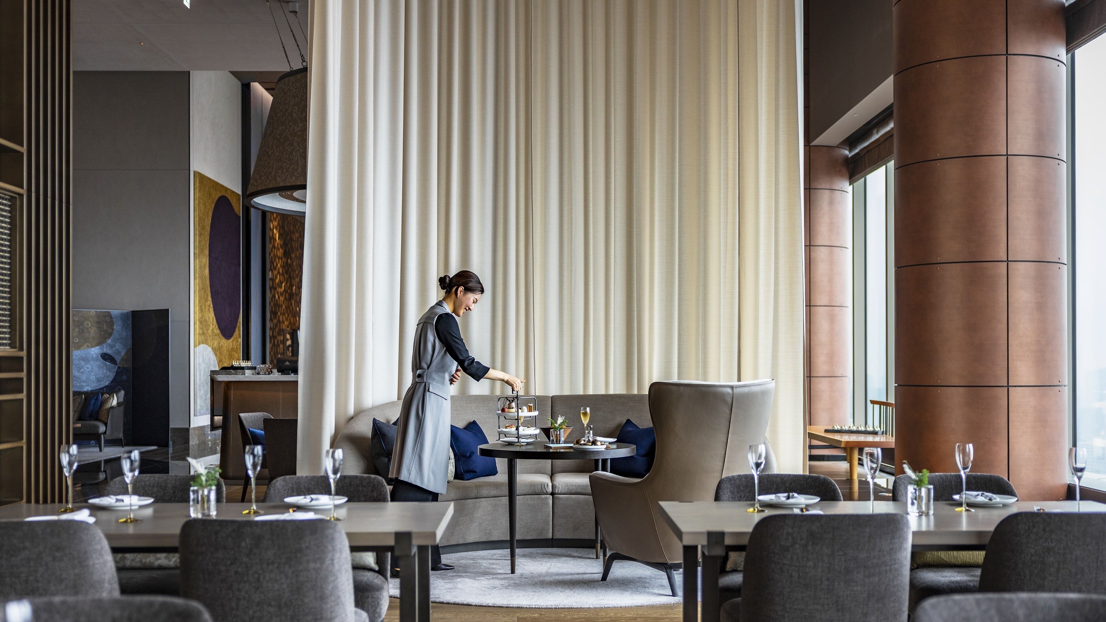 A modern dining area with a service staff attending to a table.