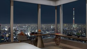 A modern hotel room with a large window offering a cityscape view, a round table with a vase, and a comfortable seating area. - Four Seasons Hotel Tokyo at Otemachi (Tokyo)