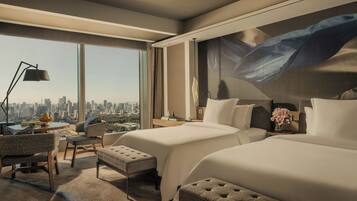 A modern hotel room with a city view, two beds, a desk, and a large abstract painting on the wall.