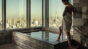 A woman in a towel standing by a glass-enclosed hot tub with a city view. - Four Seasons Hotel Tokyo at Otemachi (Tokyo)