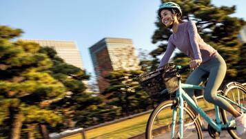 A person riding a bicycle on a path with trees and buildings in the background.