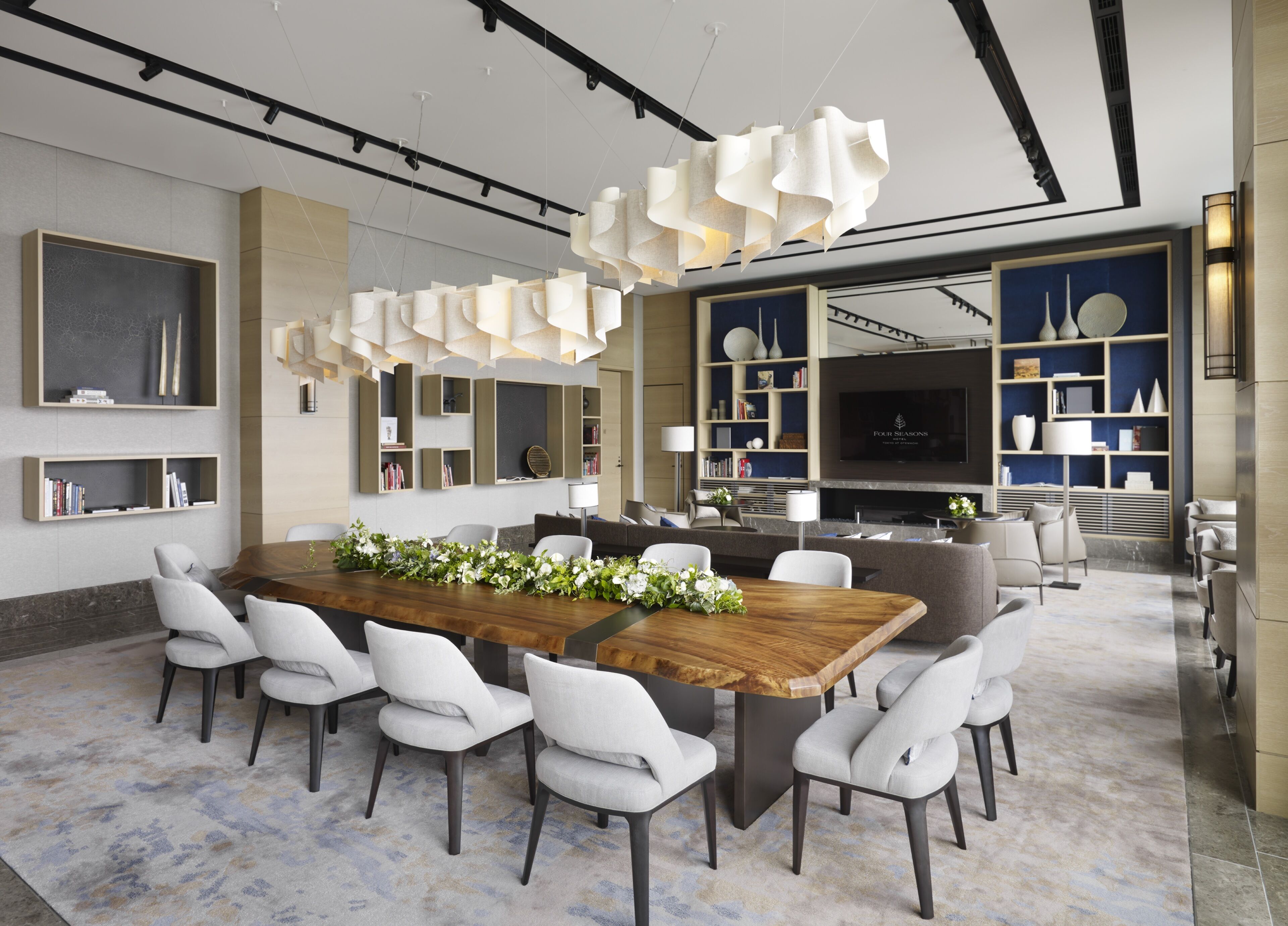A modern dining area with a wooden table, white chairs, and a decorative centerpiece.