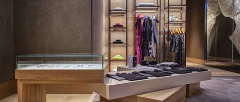 Un espace de vente moderne, doté de comptoirs d’exposition en bois, de présentoirs à vêtements et d’étagères où sont pliés les articles.