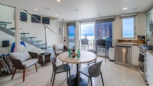 Eine moderne Küche mit Essbereich, einer Treppe und Blick aufs Meer.