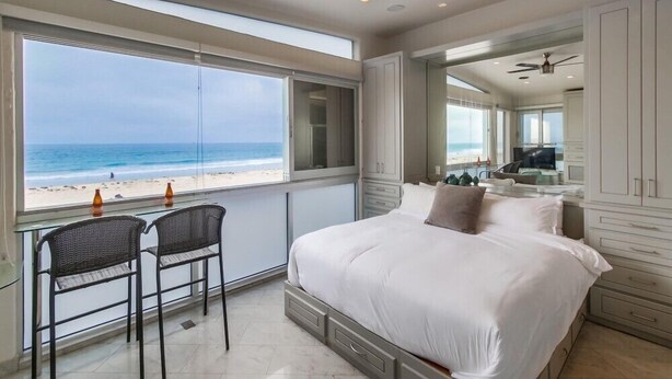 Ein Schlafzimmer mit einem großen Bett, einem Deckenventilator und Blick auf den Strand.