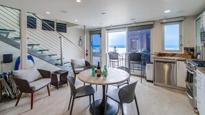 Una cocina moderna con comedor, una escalera y vista al mar.