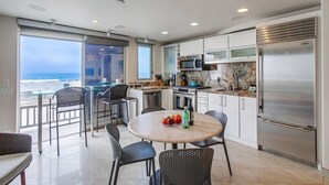 Una cocina moderna con vistas a la playa, equipada con electrodomésticos de acero inoxidable y una encimera de mármol.