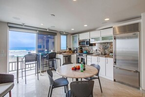 A modern kitchen with a large window overlooking the beach, a round dining table with chairs, and a stainless steel refrigerator. - 2 Levels of Ocean Front * AC * Exclusive Balcony (San Diego)