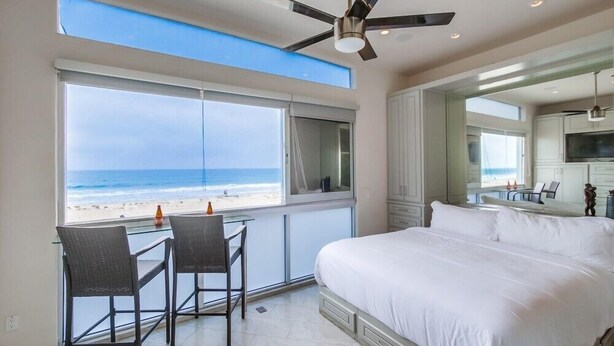 Un dormitorio con una cama grande, ventilador de techo y vista a la playa.