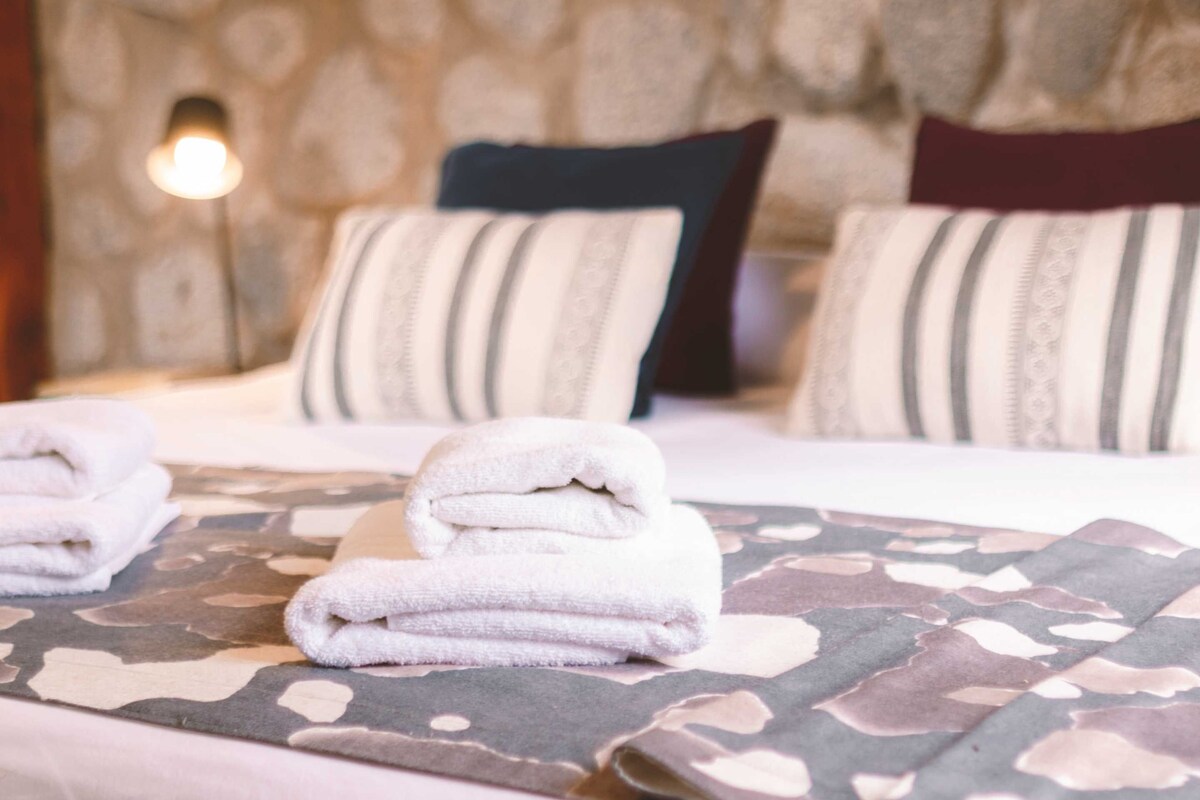 Un lit bien fait, avec des serviettes pliées, des coussins à rayures et une couvre-lit à motifs.