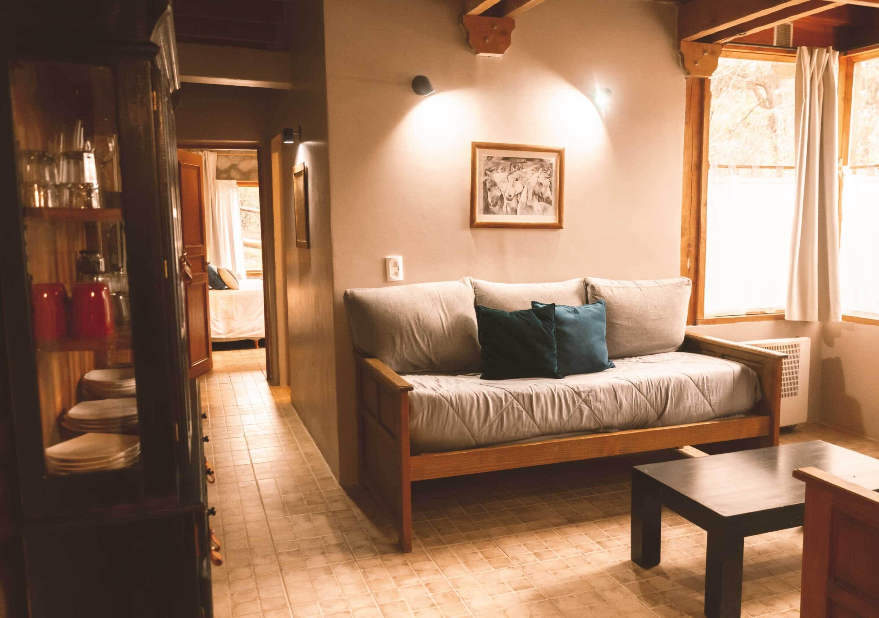 A cozy living room with a wooden sofa, a small table, and a framed picture on the wall.