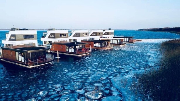 A waterfront property with floating structures, including a covered deck and a boat. - Houseboat "ELANDI" - relaxation, fun & luxury (Bitterfeld)