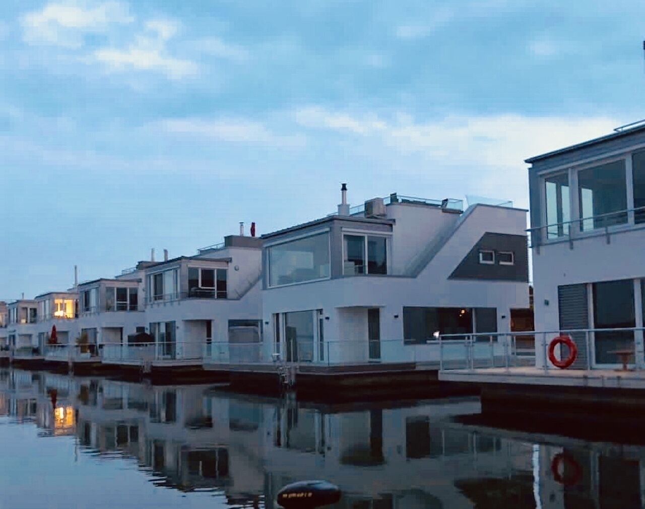A row of modern waterfront buildings with reflective water surfaces.