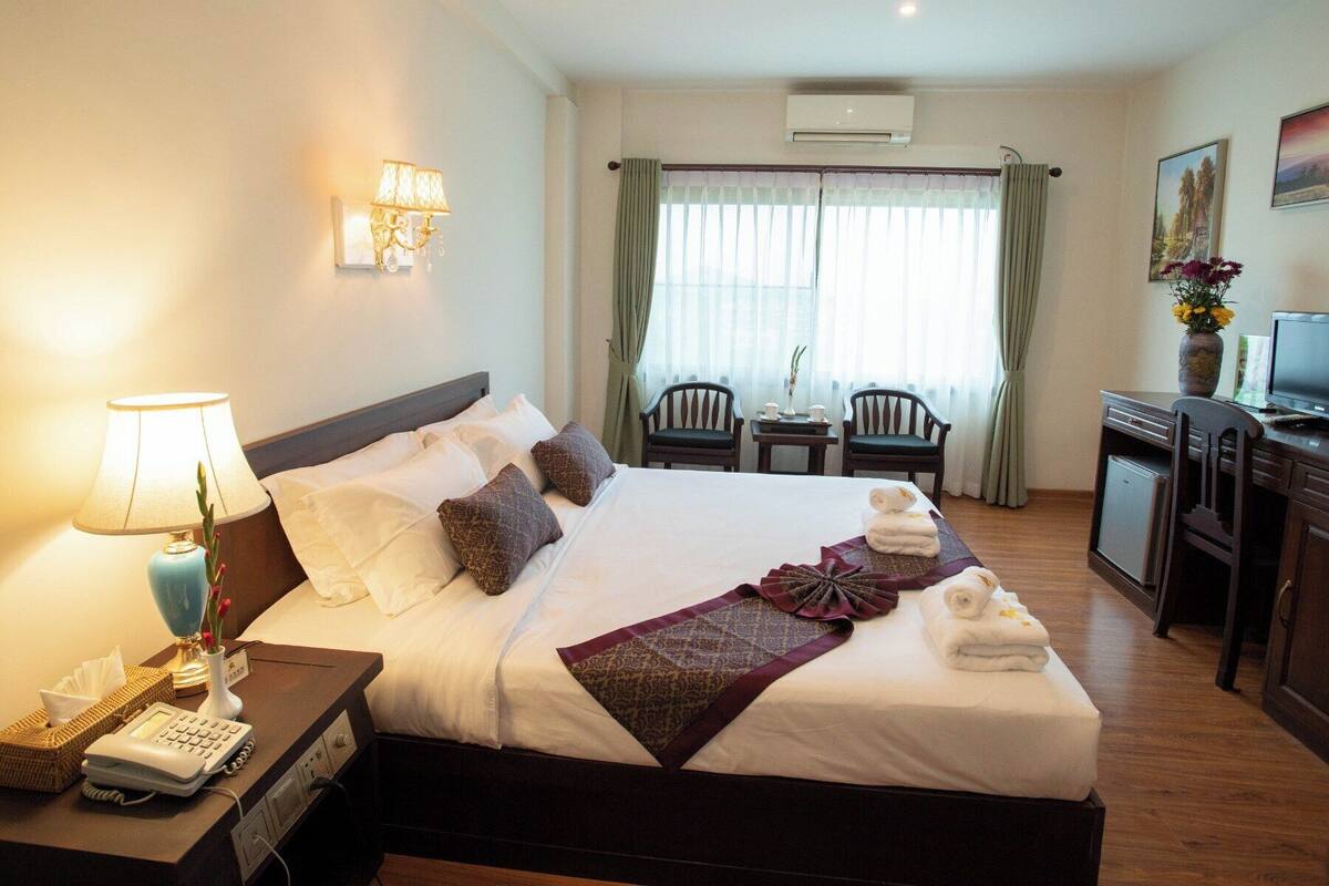 Une chambre d’hôtel équipée d’un lit, d’une lampe de chevet, d’un bureau, d’une chaise et d’un téléviseur.
