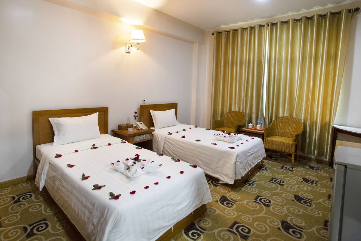 Une chambre d’hôtel avec deux lits, une chaise, un bureau et une lampe.